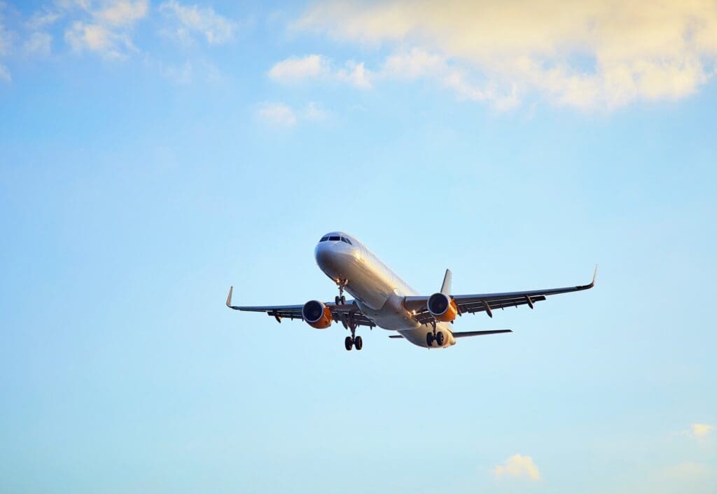 airplane flying in a blue sky with scattered clouds
